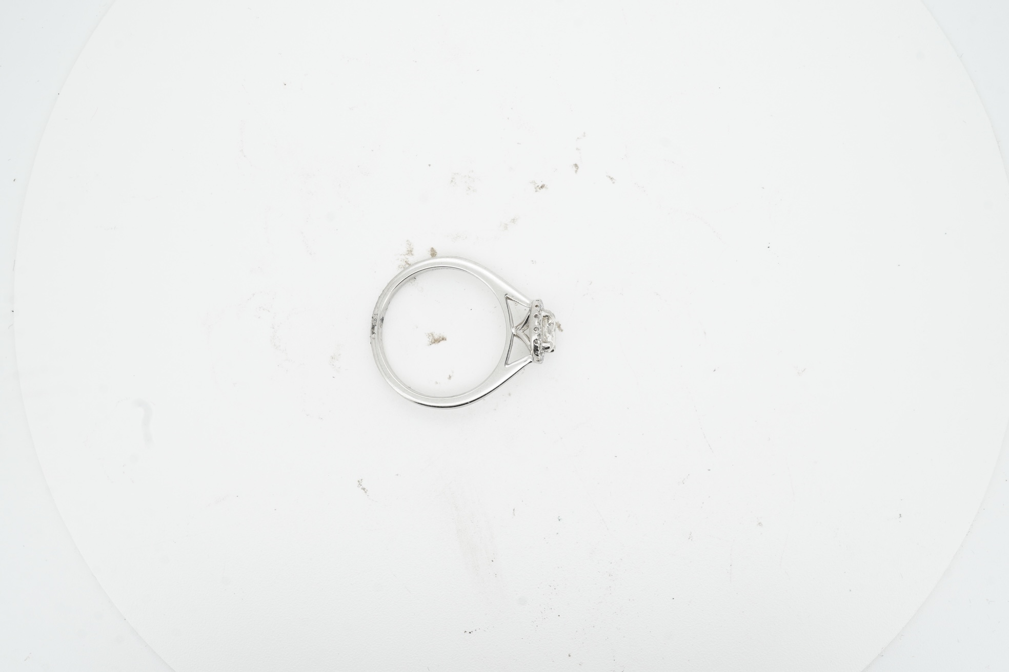 A diamond cluster ring, claw-set with a brilliant-cut diamond weighing approximately 0.70 carats, within a border of smaller brilliant-cut diamonds totalling approximately 0.10 carats, mounted in platinum, size M, Britis